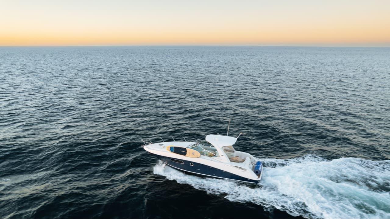 A luxury yacht anchored off the Los Cabos coast with clear blue water and desert cliffs in the background.